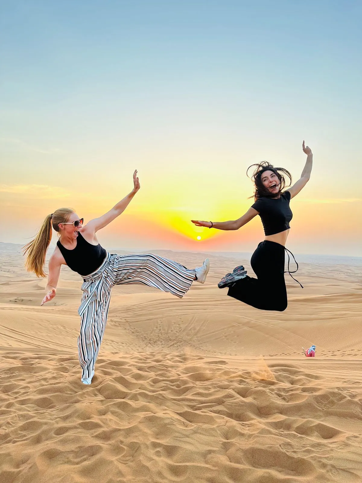 Two friends smiling on the red dunes during a Dubai desert safari
